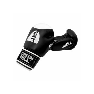 Ein Paar schwarze Echtleder-Boxhandschuhe des Modells Tiger von Green Hill vor weißem Hintergrund. Der linke Handschuh liegt auf der Seite und zeigt das weiße Green-Hill-Logo auf dem Handrücken sowie den Schriftzug Tiger. Auf dem Klettverschluss befindet sich ein schwarz-weißes Marken-Label. Der rechte Handschuh liegt leicht dahinter, sodass die Innenseite der Faust sichtbar ist.